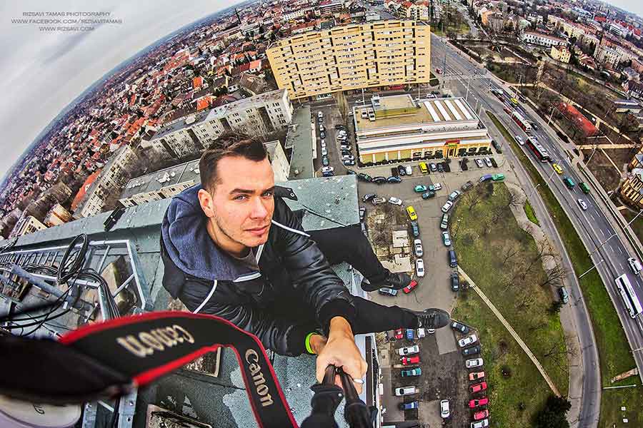 The picture was taken by a camera on a selfie stick, and shows Tamás Rizsavi standing on the edge of a tall building and a city below him. 