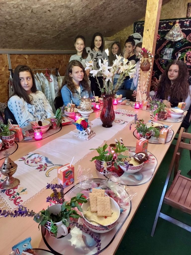 There is a group of teenagers standing around a decorated table.