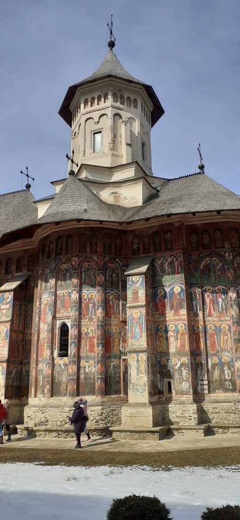 Picture of the Putna Monastery, a large church with a clocktower and colourful frescos